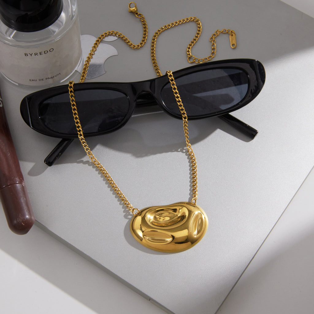 Polished swirl necklace displayed beside sunglasses