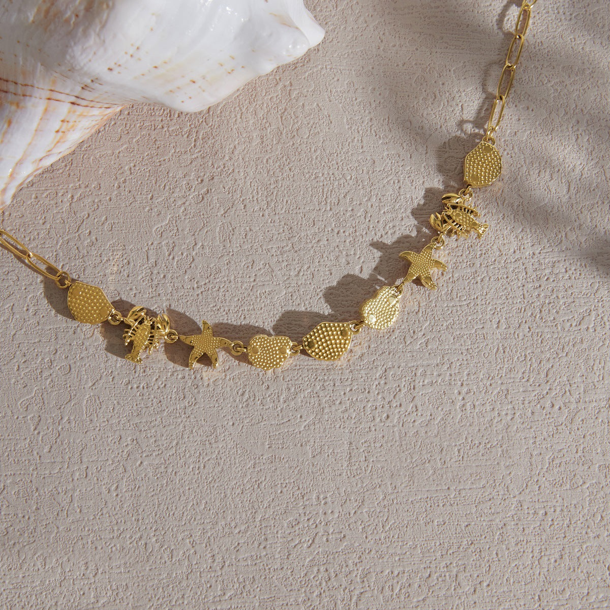 Close-up of marine charm necklace laid on sand