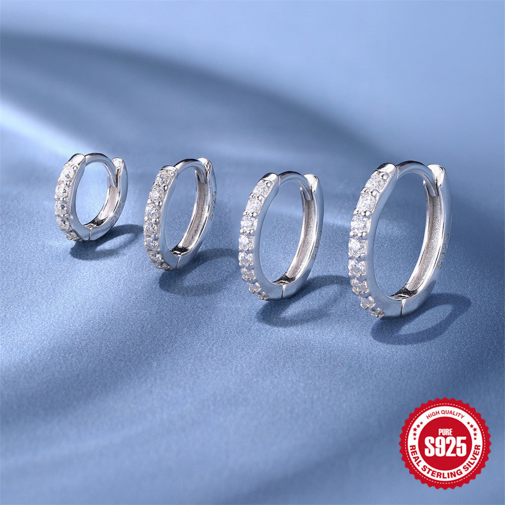 four silver-finish moissanite huggie sizes on blue fabric