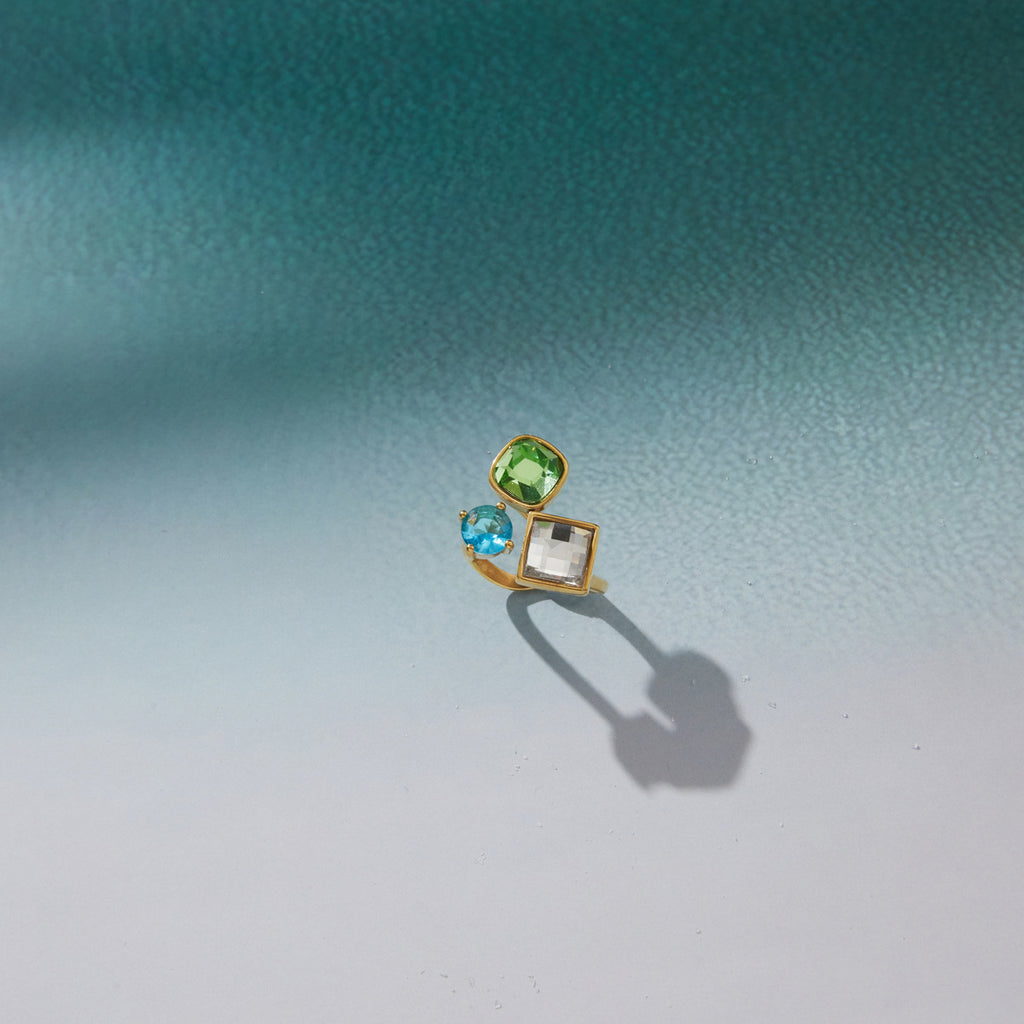 Geometric three-stone ring displayed on a pale surface