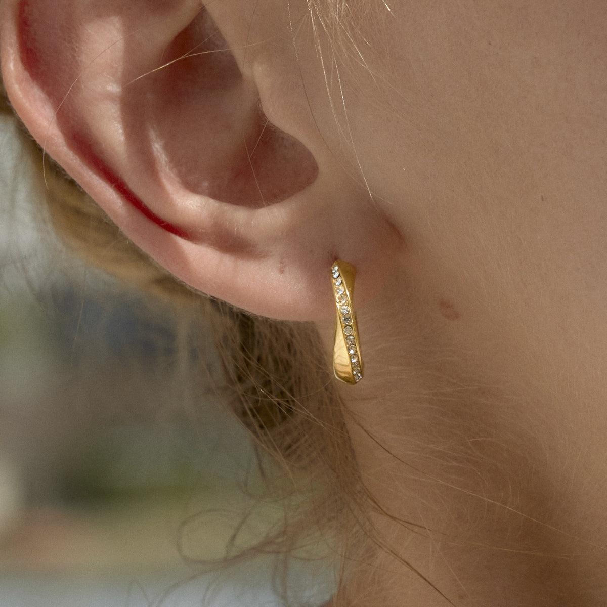 Close-up of a slim gold finish twisted hoop worn