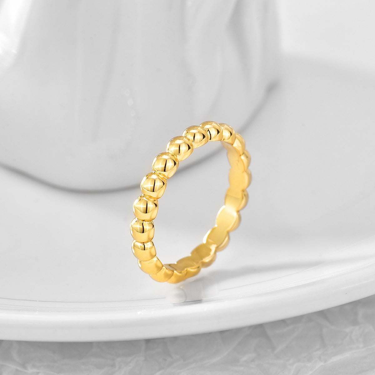 textured round bead ring displayed on a pale ceramic surface