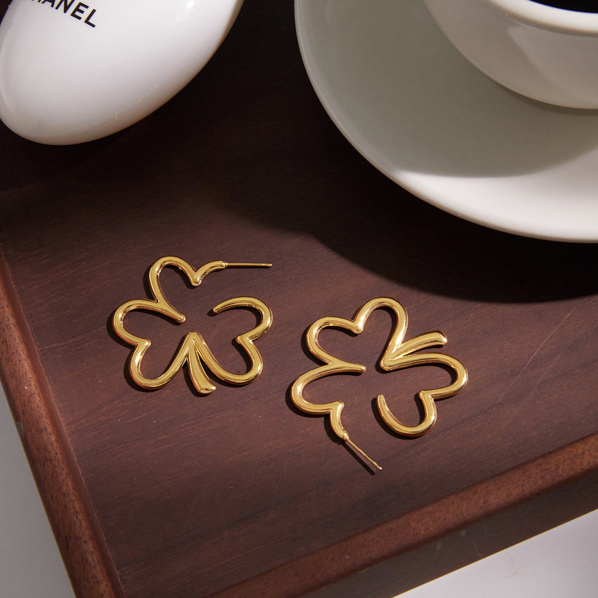 gold plated open clover earring pair on a dark wood surface