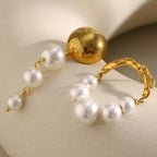 gold plated domed stud and pearl arch earrings on a stone surface