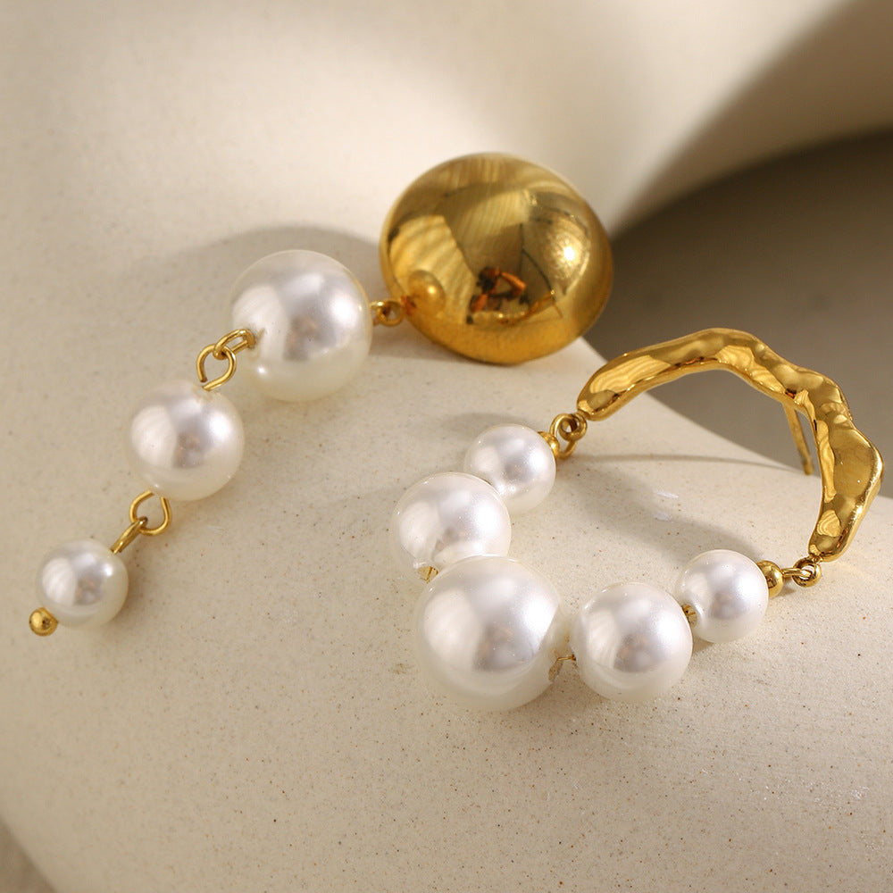 gold plated domed stud and pearl arch earrings on a stone surface