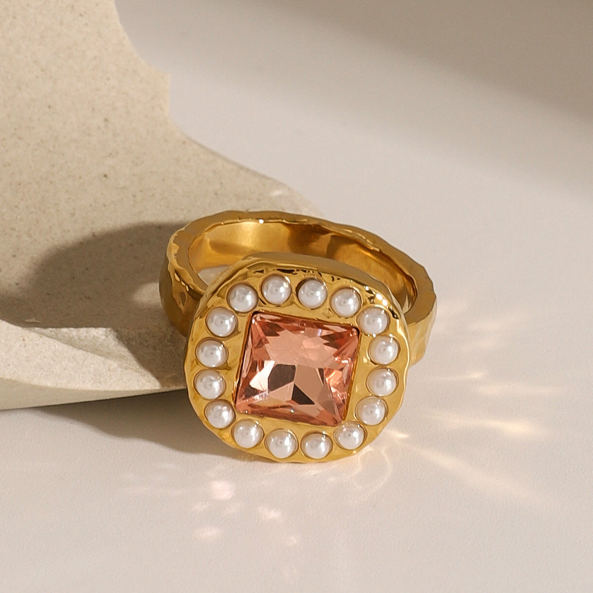 Peach stone pearl-look halo ring on a stone display