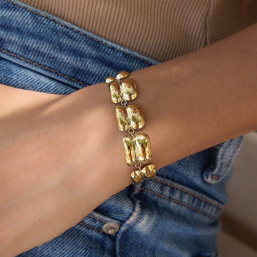 Double-ridge gold-tone bracelet worn with denim