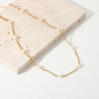 Spaced pearl necklace arranged beside a stone slab