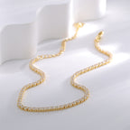 gold plated tennis chain anklet laid in a soft curve