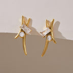 Pair of sweeping gold-tone curve earrings on a textured surface