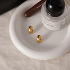 pair of polished stainless steel dome studs on a white tray