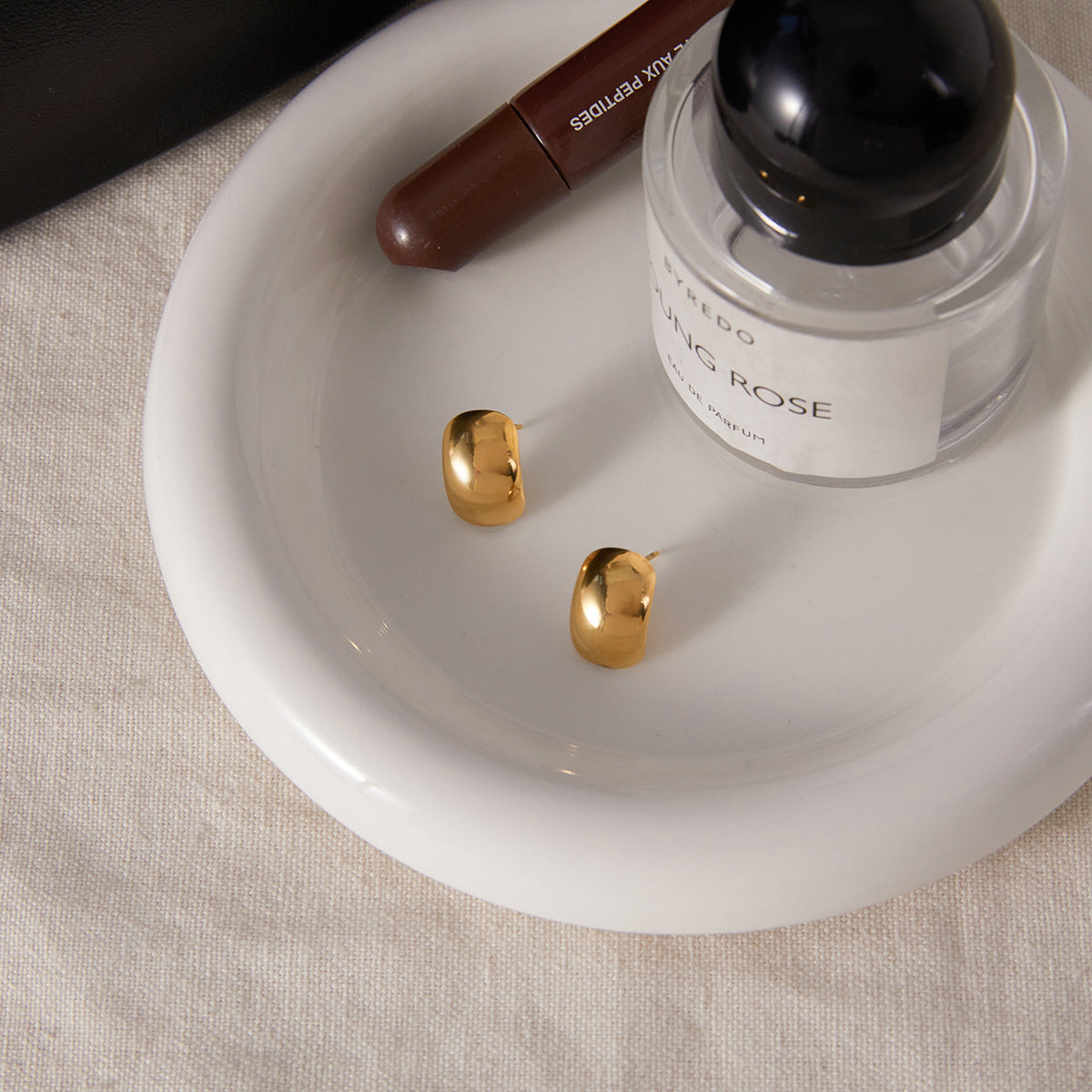 pair of polished stainless steel dome studs on a white tray