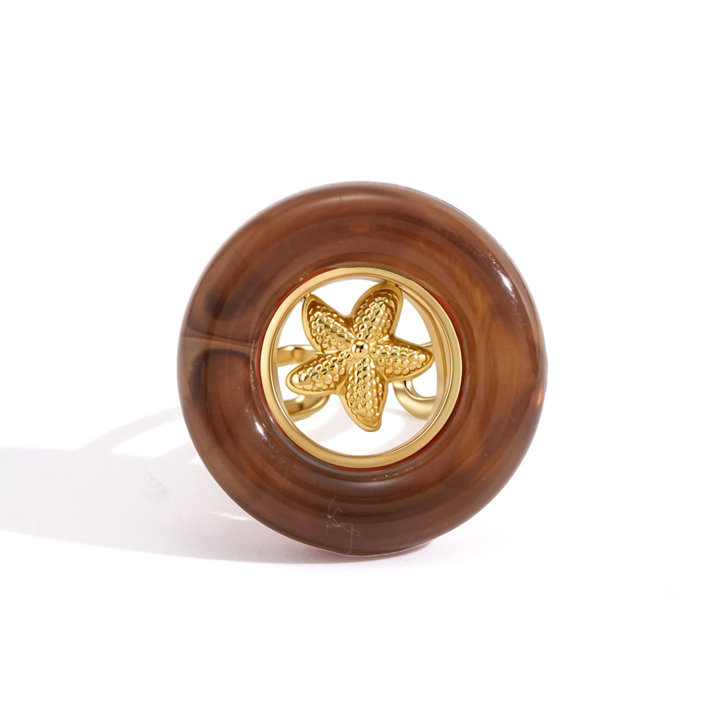 Gold tone starfish inside brown acrylic circle close-up