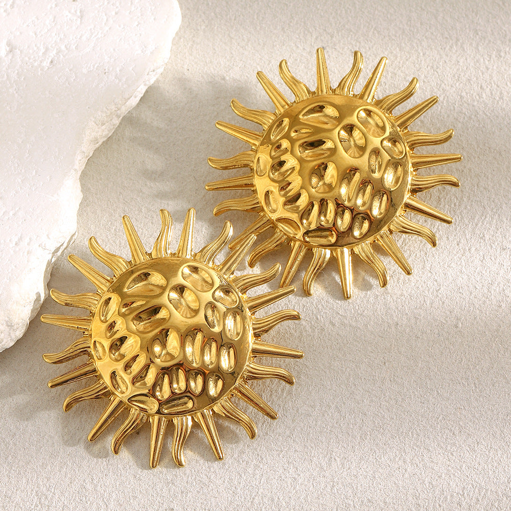 gold plated hammered sunburst statement stud earrings on a neutral surface