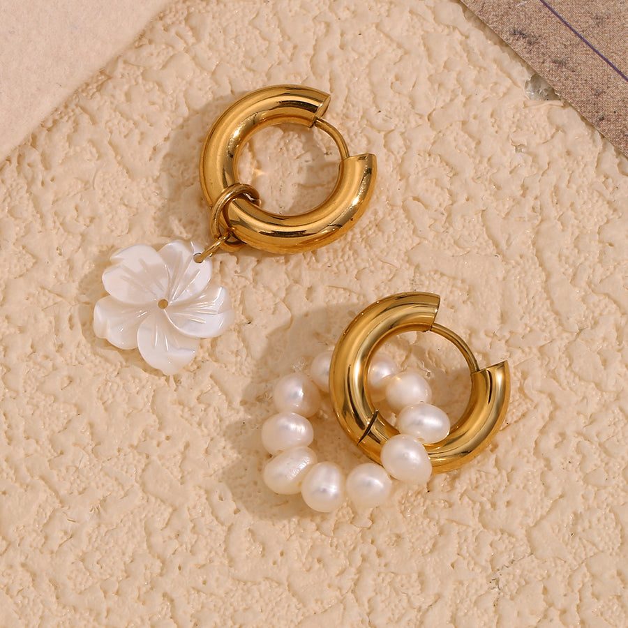 mismatched gold plated pearl and shell huggie earrings on a textured surface