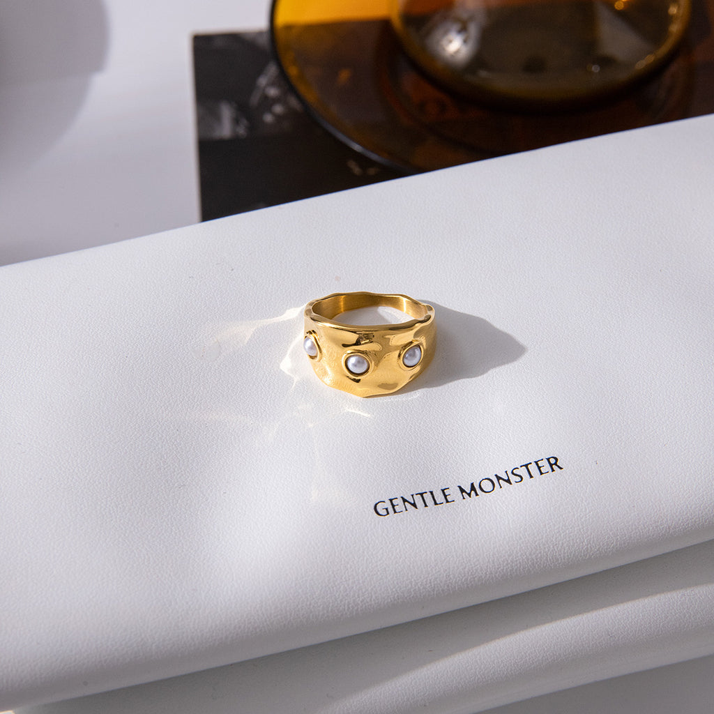 Three white accents across a gold plated ring on a book