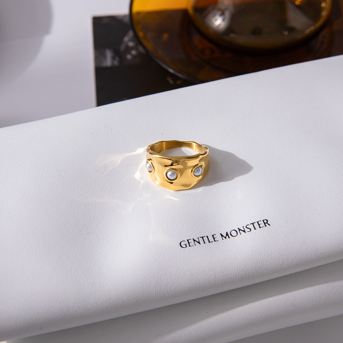 Three white accents across a gold plated ring on a book