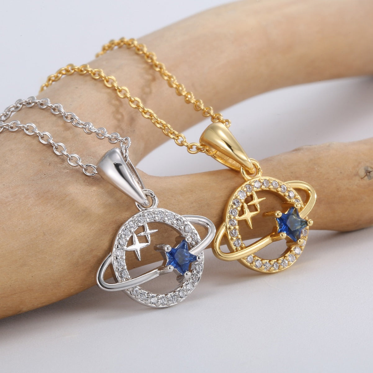 close view of ringed planet pendants with blue and clear faceted stones