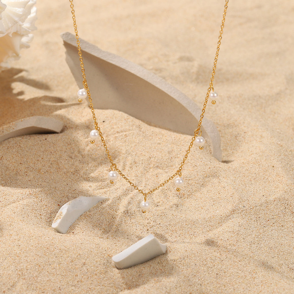 fine pearl-style station necklace arranged on a sandy display