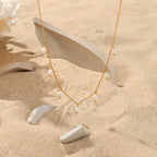 fine pearl-style station necklace arranged on a sandy display