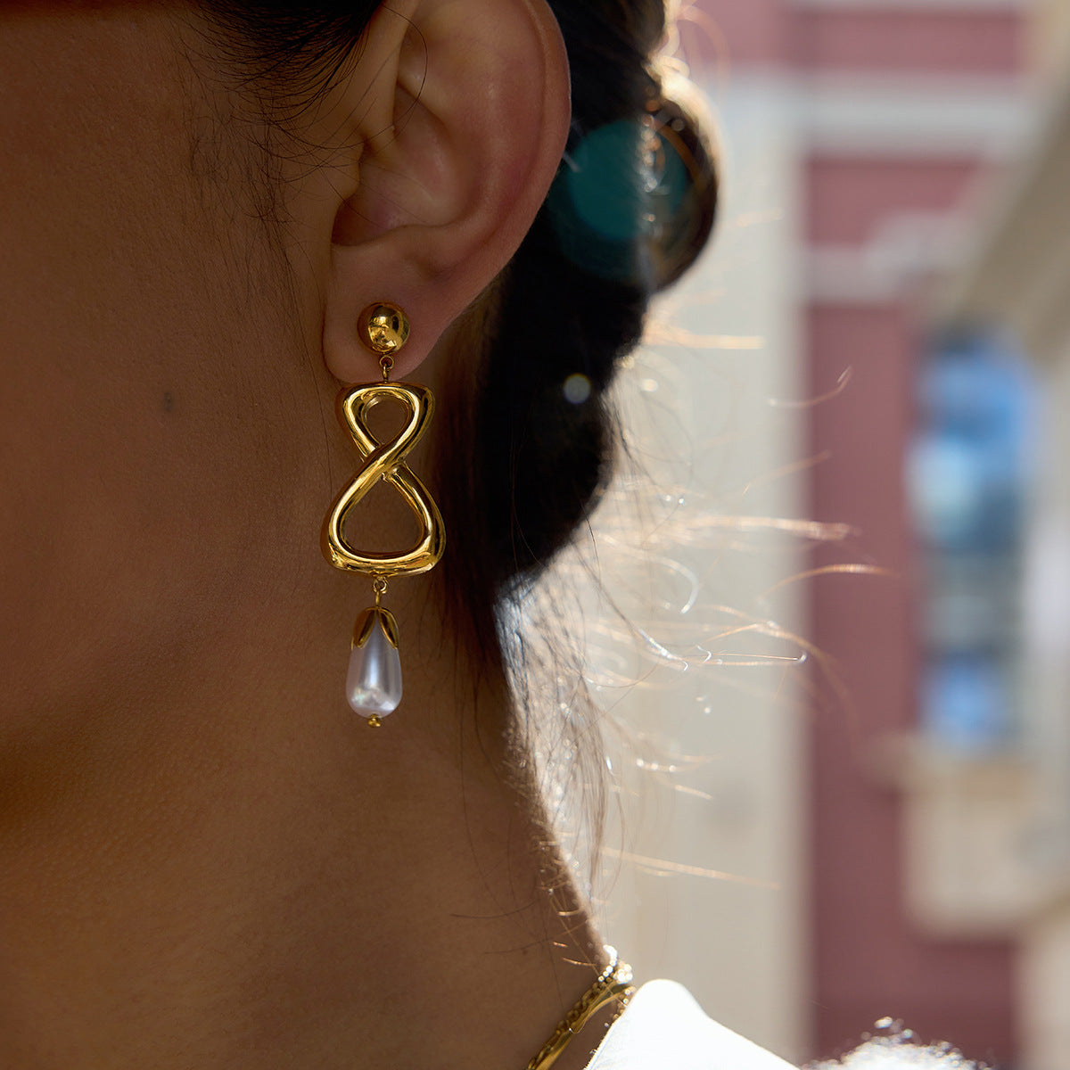 Close-up of infinity drop earrings and white pearl-look bead