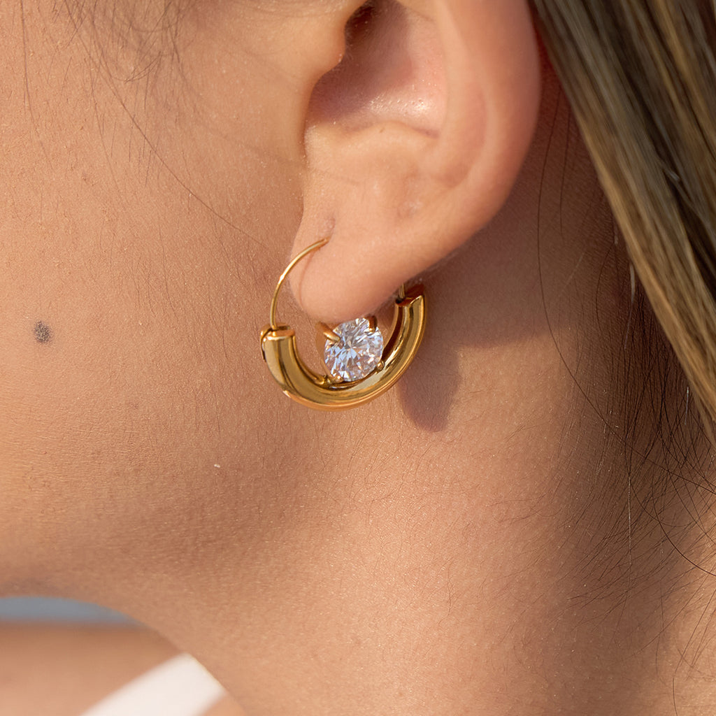 gold plated half-moon clear-stone hoop earring worn on ear