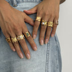 Several wide gold-tone statement rings worn on both hands