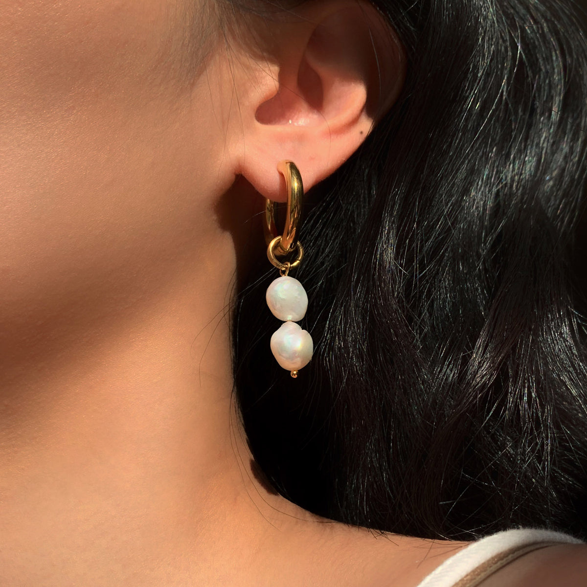 Gold-tone hoop with two freshwater pearls worn on an ear