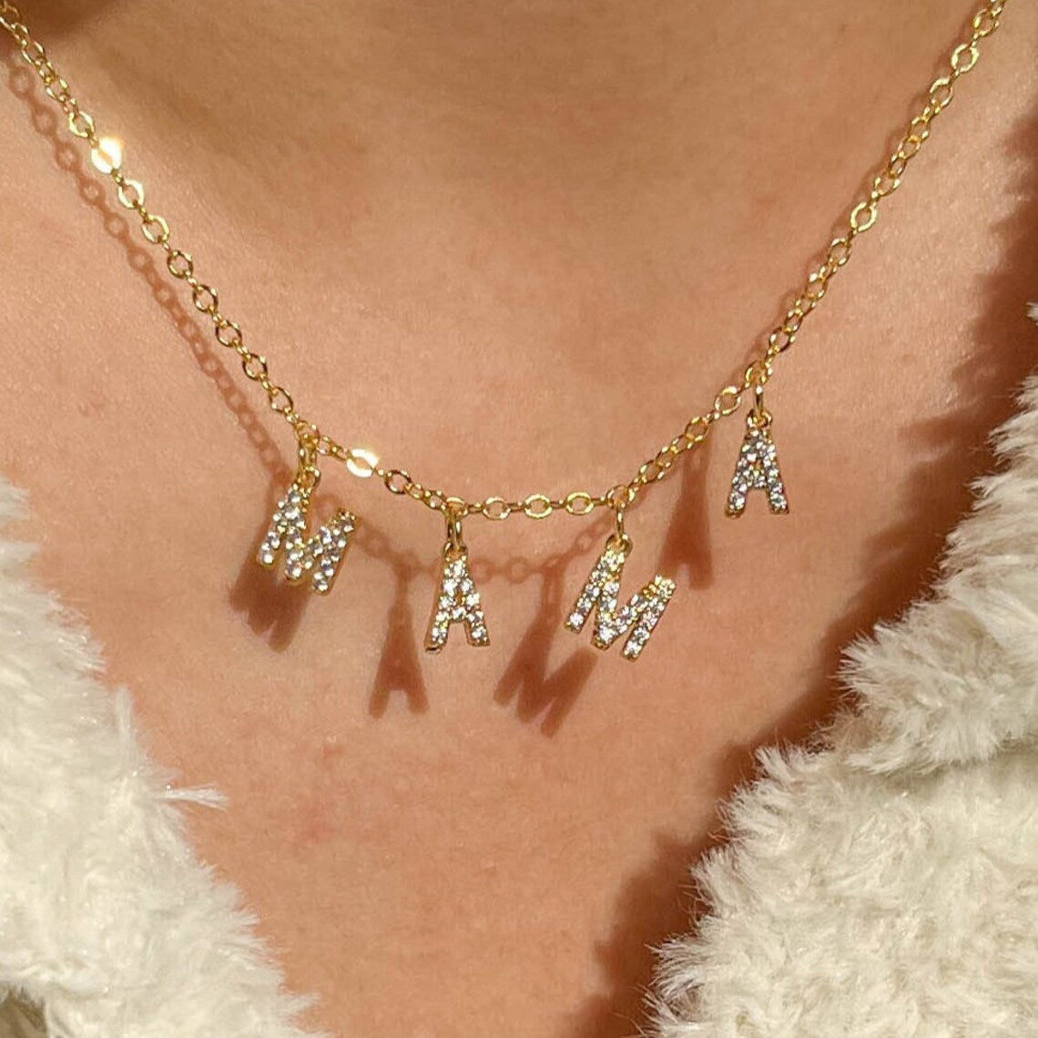 Clear accent MAMA letter necklace worn at the collar