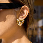 model wearing oversized gold plated sculptural heart stud earrings