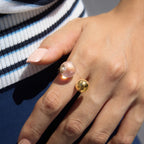Clear resin and gold-tone ball ring worn on a hand