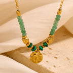 close view of translucent green beads and small gold plated coin pendant