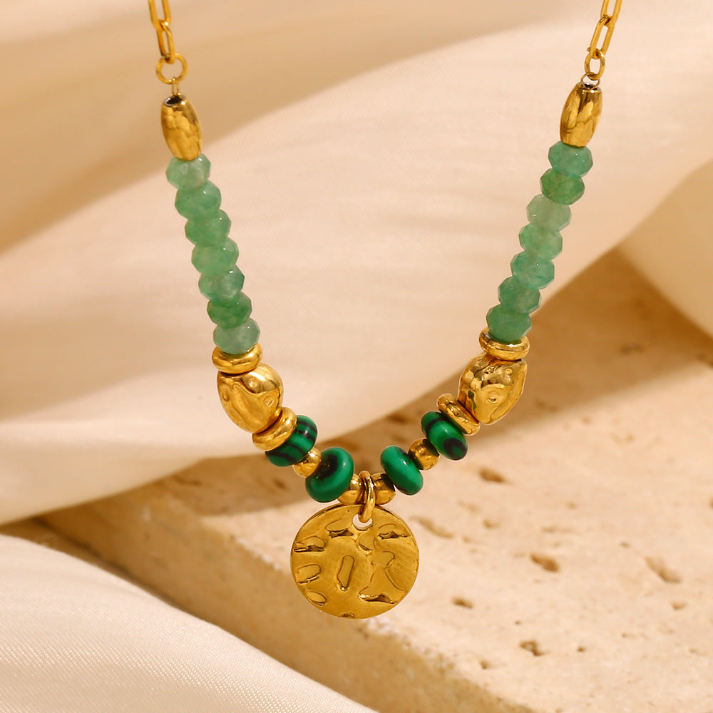 close view of translucent green beads and small gold plated coin pendant