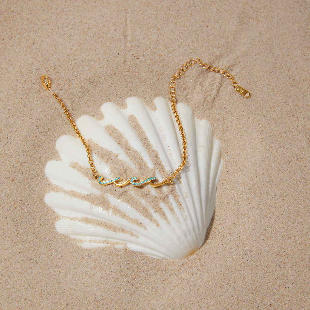 Blue accent wave bracelet arranged beside a seashell