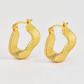 gold plated ribbed irregular hoop earrings on a white display