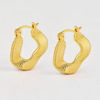 gold plated ribbed irregular hoop earrings on a white display