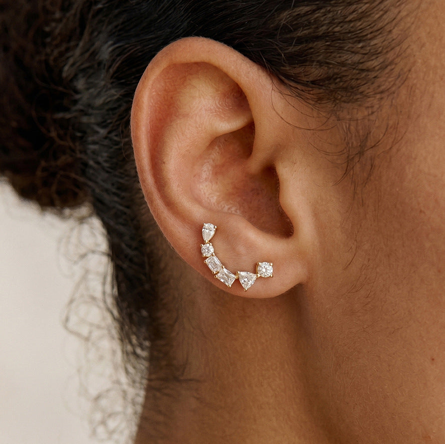 Mixed stone arc earring curving below an earlobe