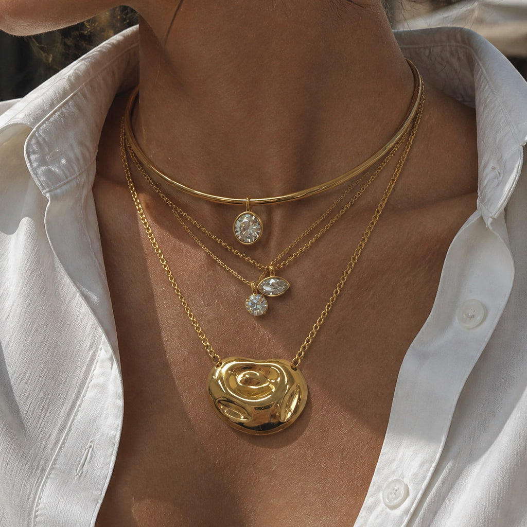 Swirl pendant necklace layered with additional necklaces