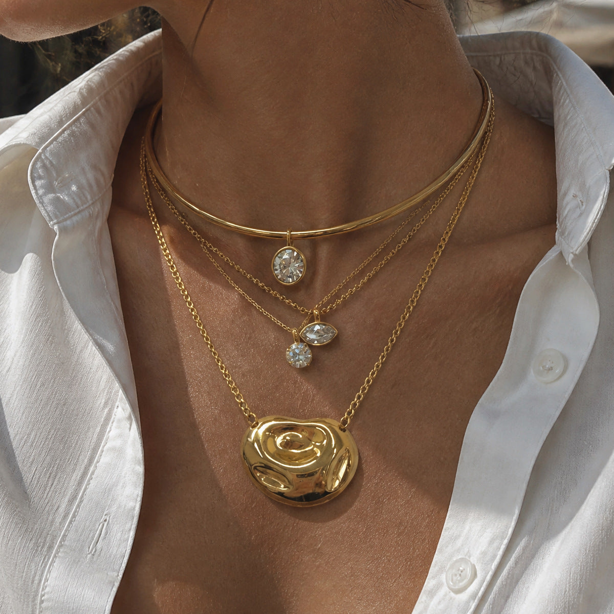 Swirl pendant necklace layered with additional necklaces