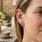 Slim gold tone earring styled with additional ear jewelry