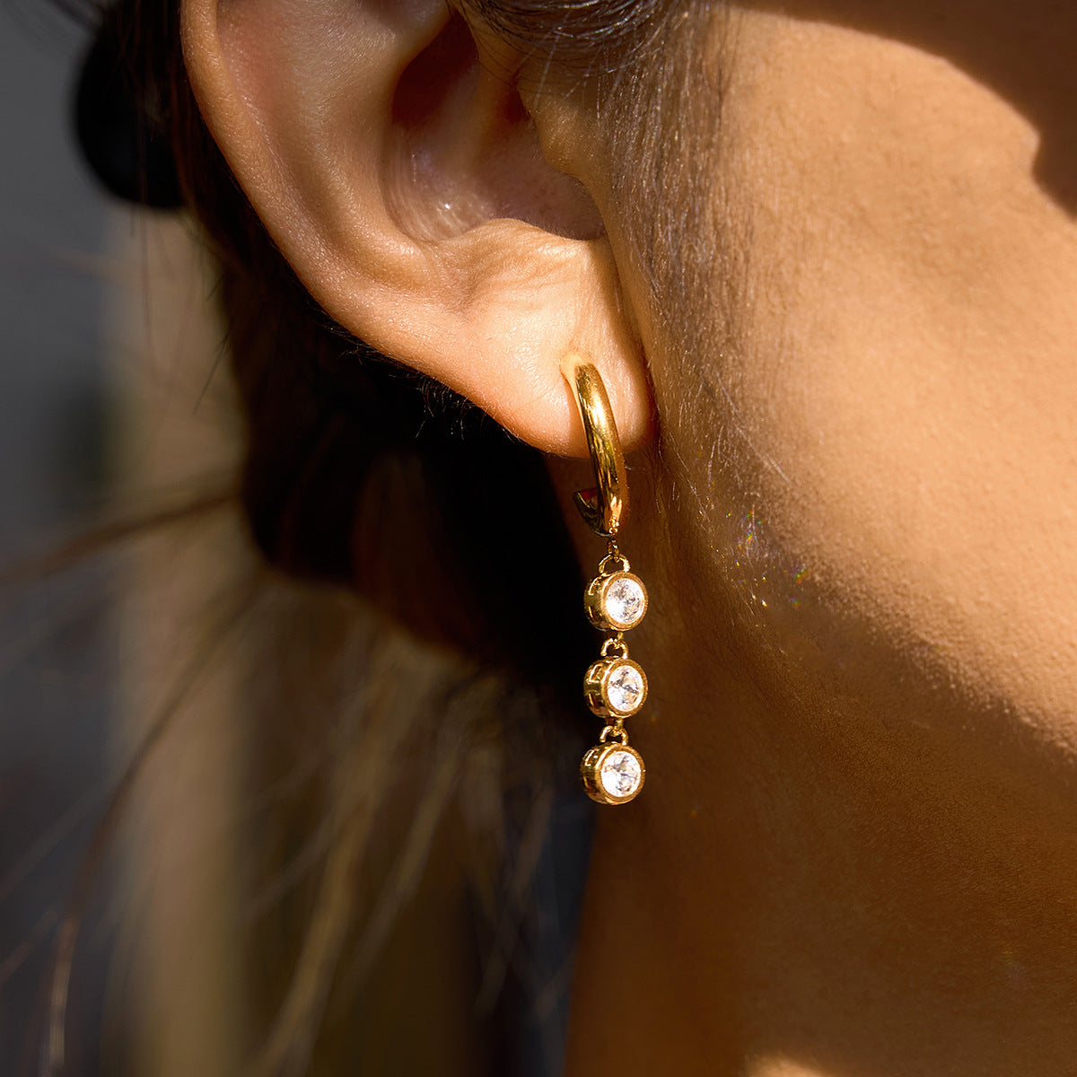 model wearing gold plated triple-stone drop hoop earring