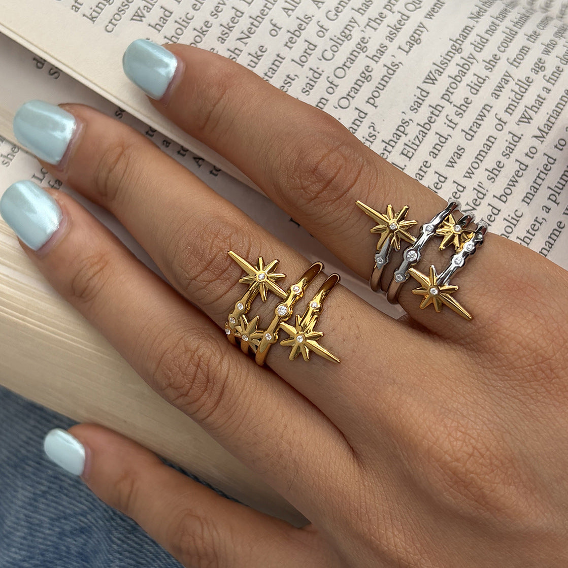Layered star rings shown on a hand holding a book
