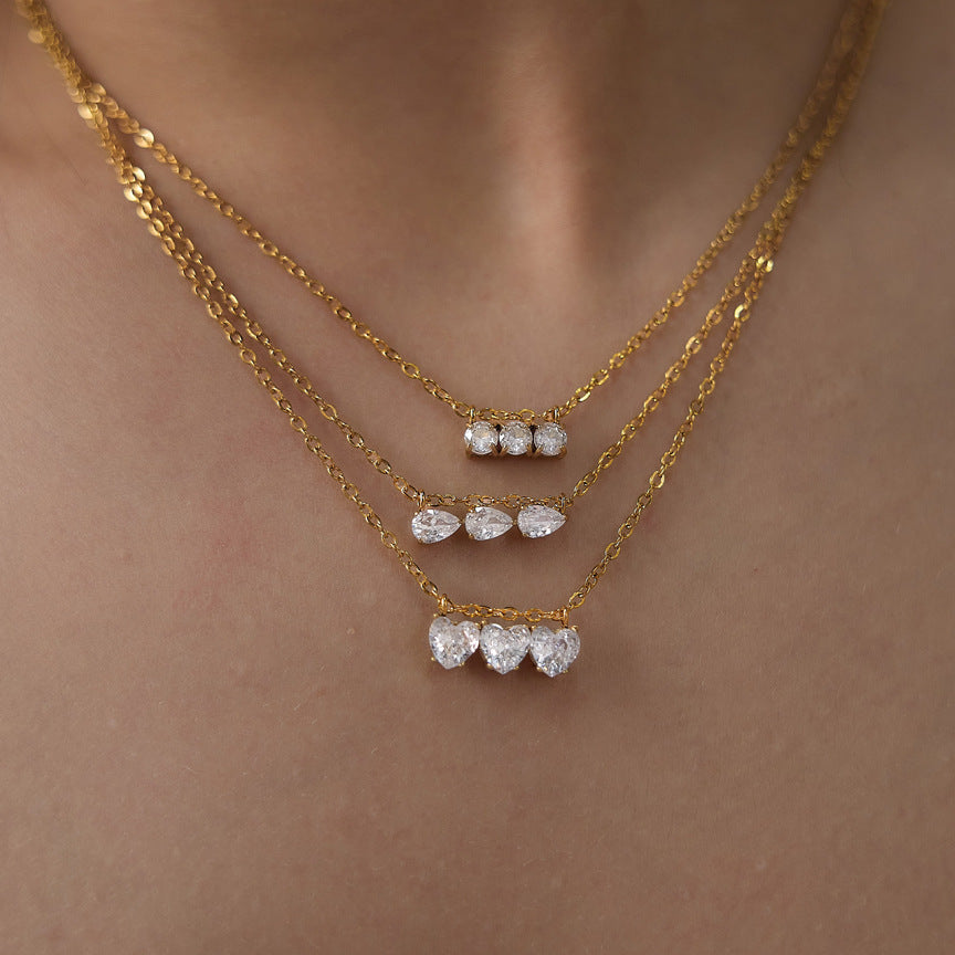 Heart, pear and round triple-stone necklaces layered on a model