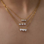 Heart, pear and round triple-stone necklaces layered on a model