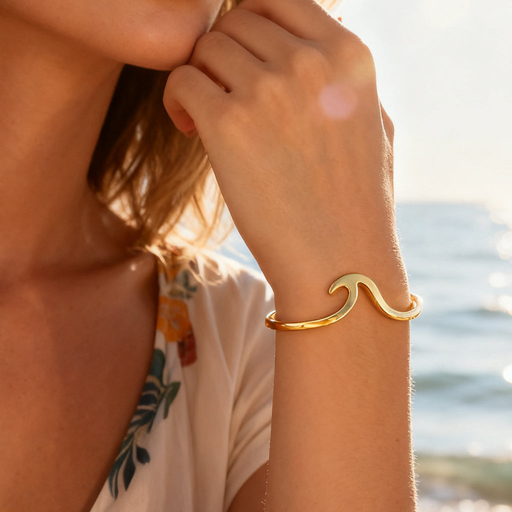 sculptural gold plated wave cuff bracelet worn by the sea