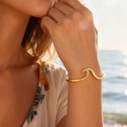 sculptural gold plated wave cuff bracelet worn by the sea