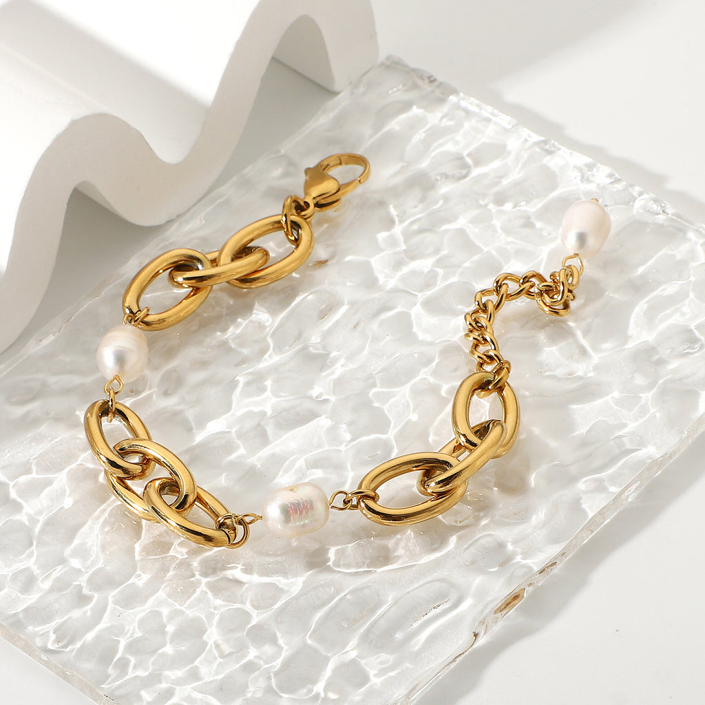 gold plated oval-link pearl bracelet on textured glass