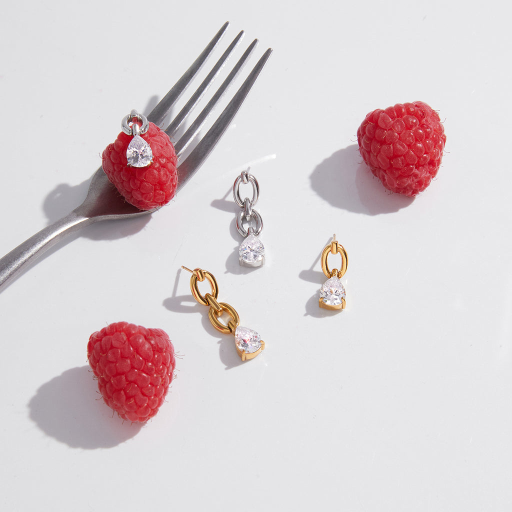 Link drop earrings styled beside raspberries and a fork