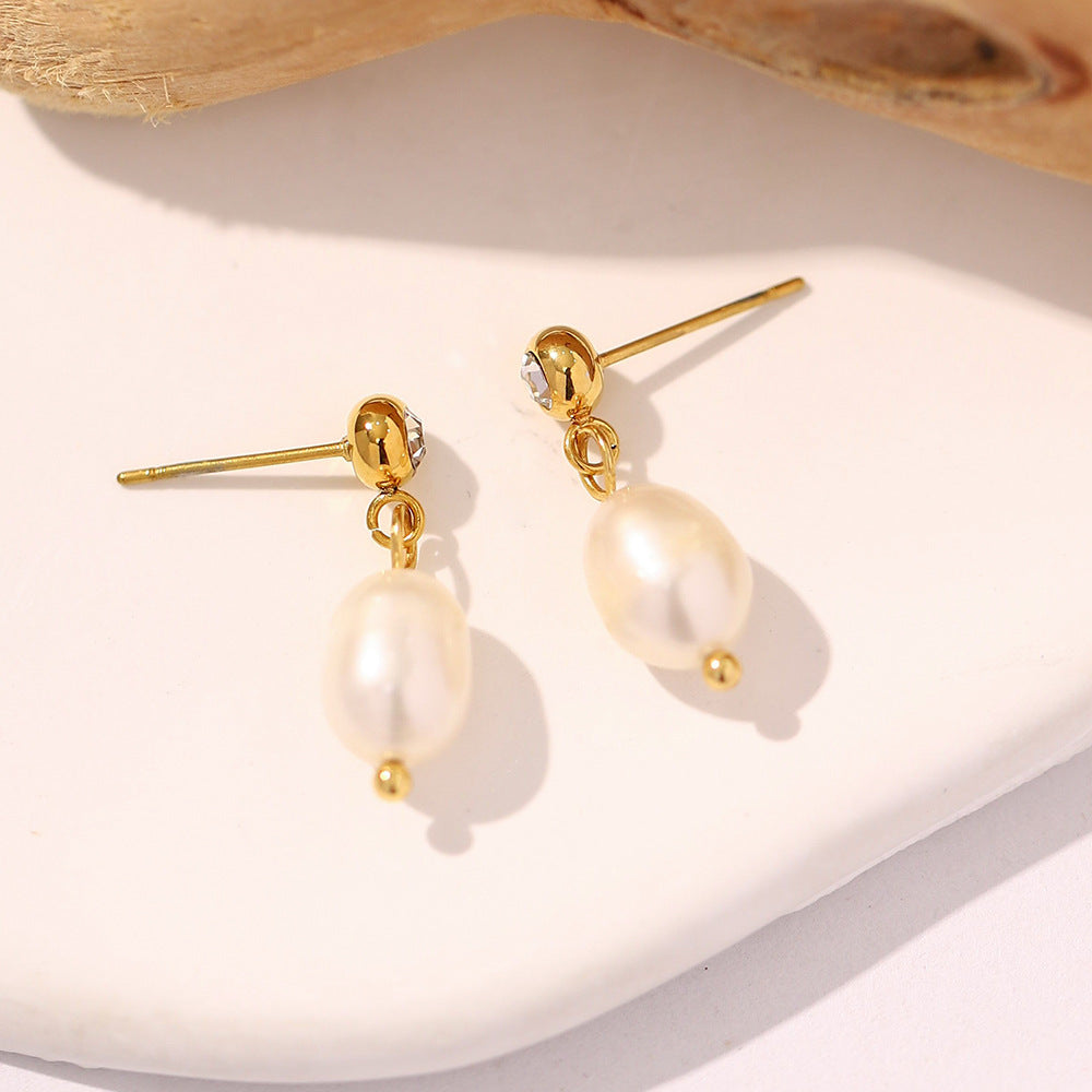 pair of gold plated pearl drop earrings with post backs on white