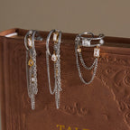 Two tone chain earrings and open ring displayed on a book